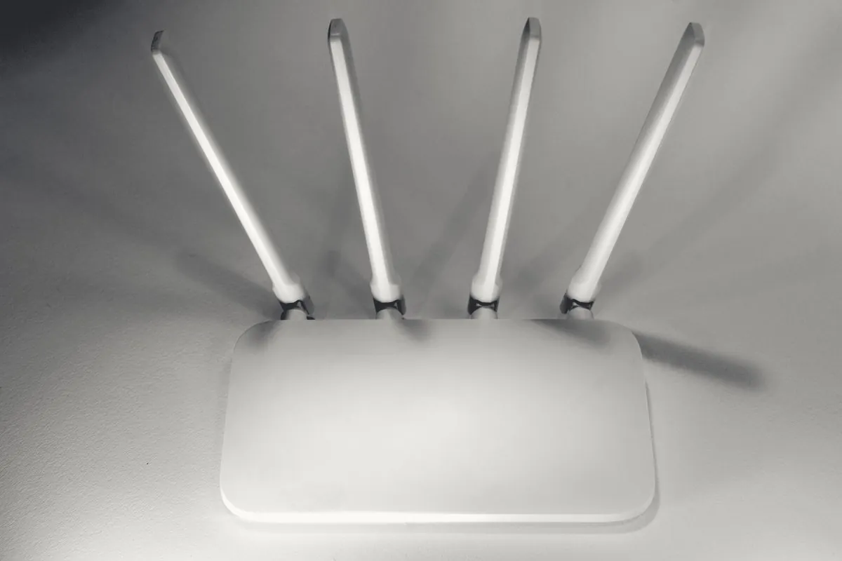 A white Wi-Fi router with four antennas on a pale surface.